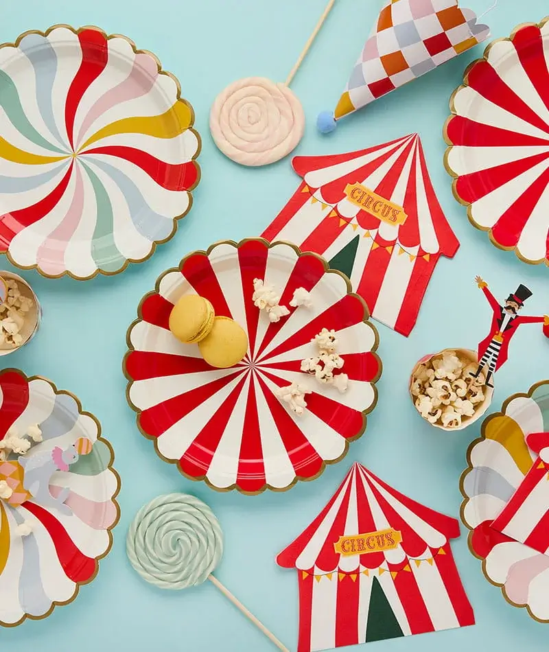 Circus-themed party tableware with striped plates, circus tent decorations, popcorn, lollipops, and colourful carnival-inspired party accessories. Circus-themed party tableware with striped plates, circus tent decorations, popcorn, lollipops, and colourful carnival-inspired party accessories.